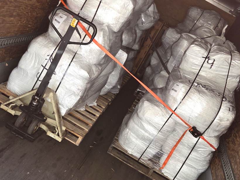 Two large strapped pallets of freight loaded inside Heavy Hitter's box truck with a pallet jack staged alongside