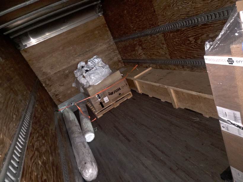 Inside Heavy Hitter's box truck with a crated pallet and wrapped freight strapped to the e-track wall